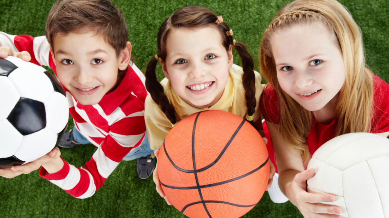 Image of happy friends on the grass with balls looking at camera